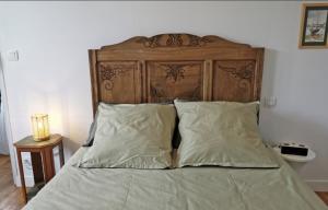 a bed with a wooden headboard and two pillows at La Maison de Soaz classée 3 étoiles in Châteauneuf-du-Faou