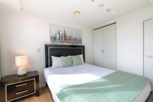 オークランドにあるSkytower and City View 2 Bedroom Apartment on High Floorのベッドルーム(大きな白いベッド1台、ナイトスタンド付)