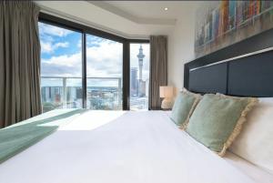 オークランドにあるSkytower and City View 2 Bedroom Apartment on High Floorの大きな窓のある大きな白いベッドのある寝室
