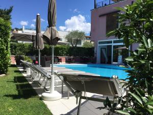 a row of chairs and umbrellas next to a pool at Hotel Villa Ca' Nova ***S in Garda