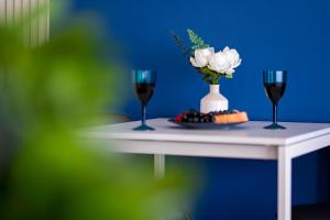 two glasses of wine and a vase of flowers on a table at Urban Elegance - Stylish Central Accommodation in Bucharest