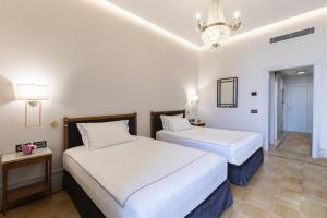 two beds in a hotel room with a chandelier at Grand Hotel Parker's in Naples