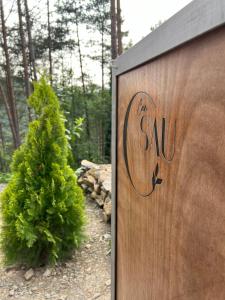 a wooden sign that reads the sau next to a bush at Can Sau in Sant Joan de les Abadesses