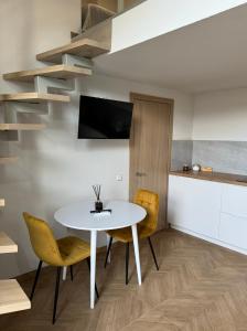 a dining room with a white table and yellow chairs at Loftas Smilga in Palanga