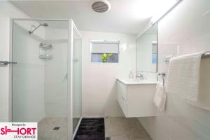 un bagno bianco con doccia e lavandino di Bright, Cosy Cottage near CBD- Free wifi, Netflix and Disney Plus a Orange