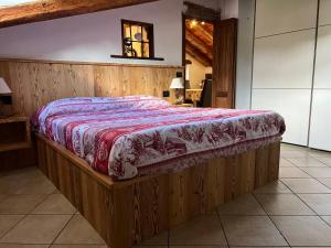 una camera da letto con un letto di legno con un piumone rosso e bianco di Maison Moline ad Aosta