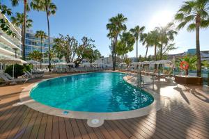 a pool on a deck with palm trees and umbrellas at Alua Boccaccio in Port d'Alcudia