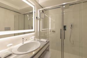 a white bathroom with a sink and a shower at Grand Hotel Parker's in Naples