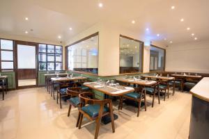 a restaurant with wooden tables and chairs and windows at Hotel Avon Ruby Dadar in Mumbai