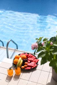 a plate of fruit and vegetables on a table next to a pool at Hotel San Međugorje in Čitluk