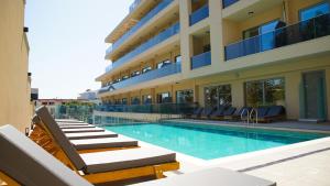 a swimming pool with lounge chairs and a building at Poseidon Beach Resort - Premium All Inclusive & Free Riviera Beach Access in Golden Sands