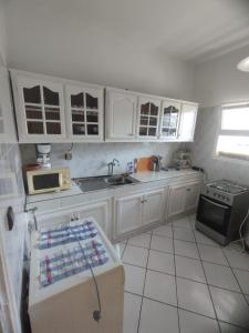 a kitchen with white cabinets and a sink and a stove at Appartement complexe Arrous Bahr mikki beach vue piscine et jardin in Tangier