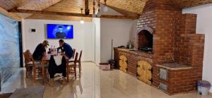 two people sitting at a table in a room with a brick oven at Alexandra si Adan in Dubova
