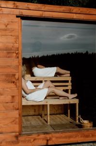 斯克拉斯卡波伦巴Zielony Jeleń - sauna i jacuzzi的两名女子躺在建筑物内的床上。