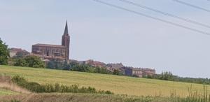 a large church in a field with a large building at Le Cosy in Caraman