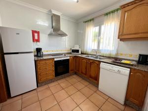 a kitchen with a white refrigerator and wooden cabinets at Villas Monte Jávea - BTB in Jávea