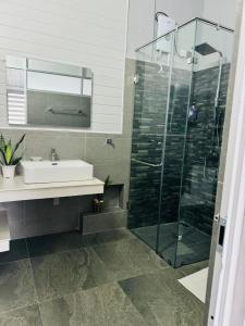 a bathroom with a sink and a glass shower at La Isla Homestay in Kandy