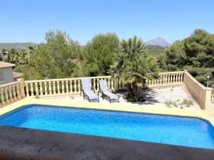 a swimming pool with two chairs and a fence at Villas Monte Jávea - BTB in Jávea