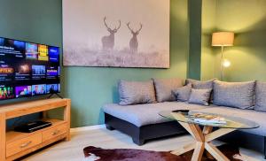 a living room with a couch and a flat screen tv at HIRSCH FeWo Brocken - Parkplatz - Zentral in Bad Harzburg