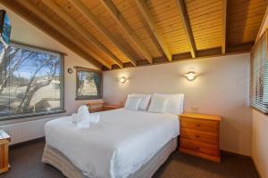 a bedroom with a large white bed and a window at Tambo in Dinner Plain