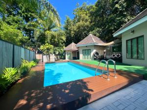 a swimming pool with a wooden deck and a house at Avare House Krabi in Ao Nam Mao +65 photos