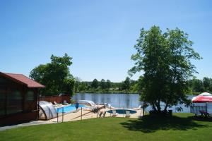 a backyard with a swimming pool next to a lake at Dom Wczasowy Nadrzecze in Brok