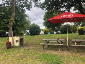 a picnic table with a red umbrella in a park at Camping Au Lac Du Drennec Glamping Tent in Commana +5 photos