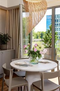 una mesa de comedor con sillas y un jarrón de flores en cohost I New Apt w-Balcony I Air Condition I Free Parking & Netflix I By Botanical Park, en Kaunas