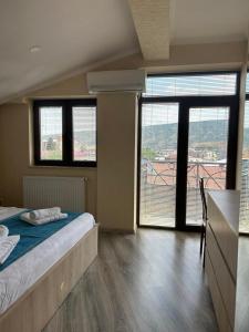 a bedroom with a bed and large windows with a view at Tbilisi Center Hotel in Tbilisi City