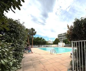 a swimming pool with people sitting around it at Studio bord de mer in Fréjus
