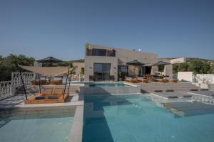 a large swimming pool with chairs and a house at Bliss Villas in Rethymno Town