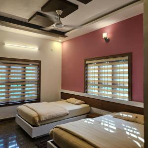 two beds in a room with pink walls and windows at Bridge Point Home Stay in Kushālnagar +29 photos