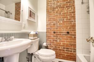 a bathroom with a white toilet and a brick wall at Historic Mountain Loft with GREAT Views in Leadville +14 photos