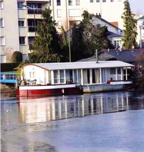 a boat with a house on the side of a river at Charmante Péniche - Séjour atypique Nantes in Nantes