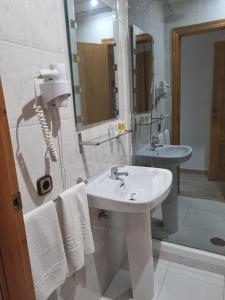 een witte badkamer met een wastafel en een spiegel bij Hostal Calaverde in Villaricos
