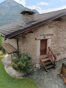 un piccolo edificio in pietra con una porta di legno e un portico di Casa delle Rose - Marmora a Marmora
