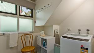 a laundry room with a washer and a chair at The Cubby in Dinner Plain +1 photo