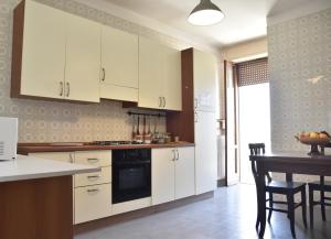 a kitchen with white cabinets and a table with chairs at VERETO apartaments Lecce in Lecce