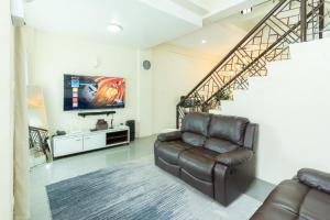 a living room with a leather couch and a tv at Tagaytay Overlooking Taal. Free Parking Fast Wi-Fi in Tagaytay +39 photos