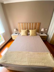 a bedroom with a large bed with two tables and two lamps at Apartamento nuevo en Zona Baja de Cotolino in Castro-Urdiales