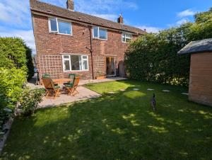 a house with a yard with chairs and a table at Cosy Single Room l Smart TV l 5 Minute Walk from Train Station in Bolton