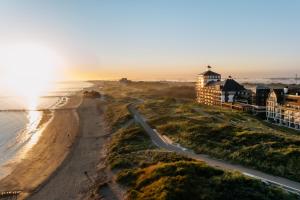een uitzicht op het strand en de oceaan bij zonsondergang bij Strandhotel in Cadzand-Bad