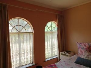 a bedroom with two windows and a bed with a bedspread at 54 Martjie laan in Brits