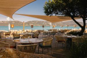 a restaurant with tables and chairs and the ocean at H&ocirc;tel Marina Corsica in Porto-Vecchio