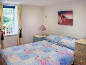 ein Schlafzimmer mit einem Bett mit einer blauen und rosa Decke in der Unterkunft Orchard Cottage in Pwllheli