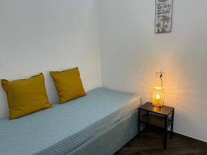 a bed with yellow pillows and a table with a lamp at North Wind Luxury Home in Vieste
