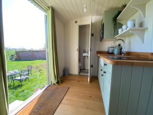 a kitchen with a sink and a view of a yard at Shepherd Huts on a Farmstay in Michelmersh