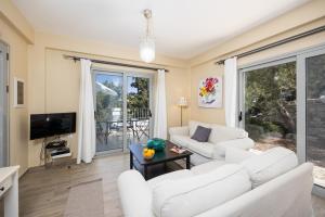a living room with two white couches and a tv at Villa Marmari in Longos