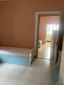 Un dormitorio con una cama y una puerta a una habitación con refrigerador. en Aulona's Garden, en Vlorë