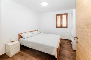 a white bedroom with a bed and a window at Apartma Oljka in Ankaran